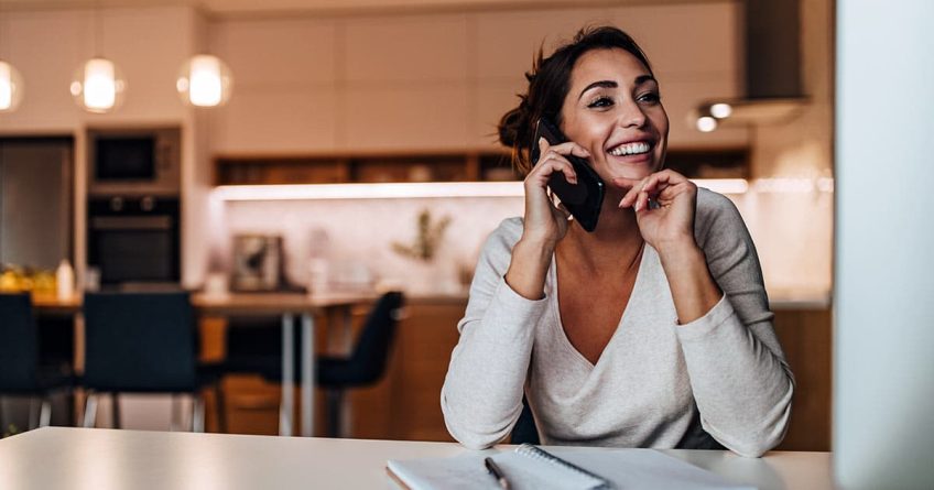 Smiling woman using phone and computer